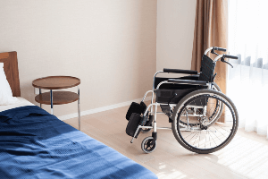 empty bed and wheelchair in a nursing home
